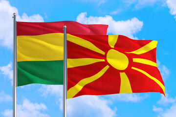 Macedonia and Bolivia national flag waving in the windy deep blue sky. Diplomacy and international relations concept.