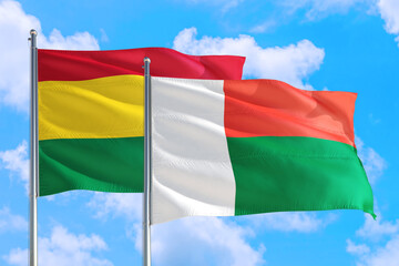 Madagascar and Bolivia national flag waving in the windy deep blue sky. Diplomacy and international relations concept.
