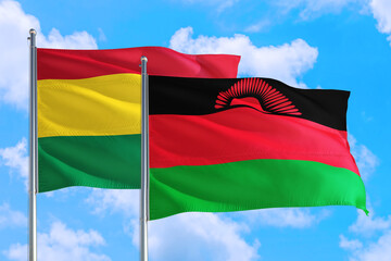 Malawi and Bolivia national flag waving in the windy deep blue sky. Diplomacy and international relations concept.