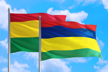 Mauritius and Bolivia national flag waving in the windy deep blue sky. Diplomacy and international relations concept.