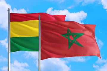 Morocco and Bolivia national flag waving in the windy deep blue sky. Diplomacy and international relations concept.