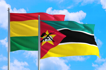 Mozambique and Bolivia national flag waving in the windy deep blue sky. Diplomacy and international relations concept.