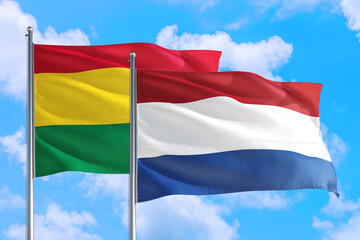 Netherlands and Bolivia national flag waving in the windy deep blue sky. Diplomacy and international relations concept.