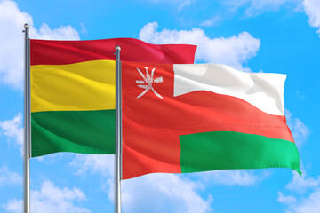 Oman and Bolivia national flag waving in the windy deep blue sky. Diplomacy and international relations concept.