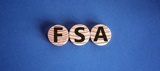 Concept word 'FSA - flexible spending account' on wooden circles on a beautiful blue background....