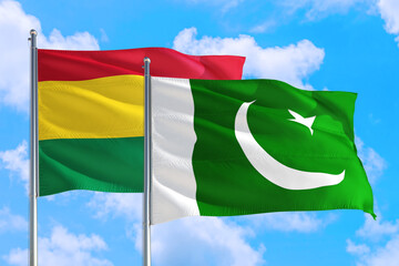 Pakistan and Bolivia national flag waving in the windy deep blue sky. Diplomacy and international relations concept.