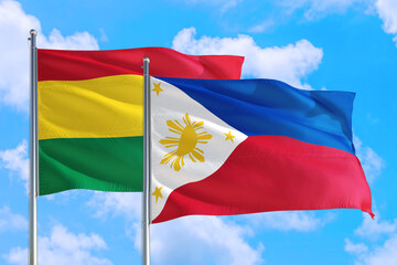 Philippines and Bolivia national flag waving in the windy deep blue sky. Diplomacy and international relations concept.