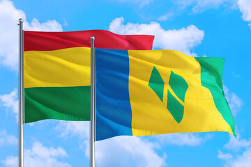 Saint Vincent And The Grenadines and Bolivia national flag waving in the windy deep blue sky. Diplomacy and international relations concept.