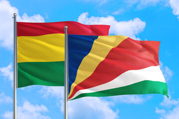 Seychelles and Bolivia national flag waving in the windy deep blue sky. Diplomacy and international relations concept.