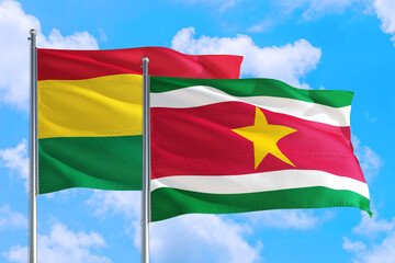 Suriname and Bolivia national flag waving in the windy deep blue sky. Diplomacy and international relations concept.