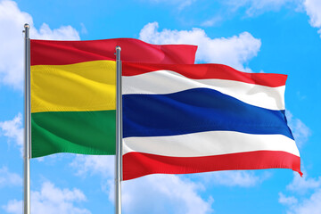 Thailand and Bolivia national flag waving in the windy deep blue sky. Diplomacy and international relations concept.