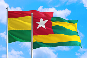 Togo and Bolivia national flag waving in the windy deep blue sky. Diplomacy and international relations concept.