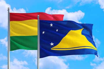 Tokelau and Bolivia national flag waving in the windy deep blue sky. Diplomacy and international relations concept.