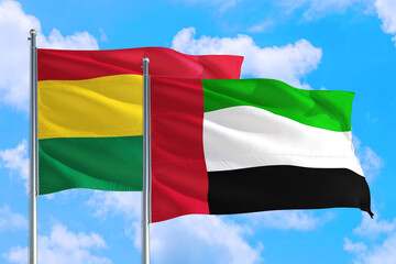 United Arab Emirates and Bolivia national flag waving in the windy deep blue sky. Diplomacy and international relations concept.