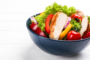 Delicious salad with chicken and vegetables on white wooden table, closeup
