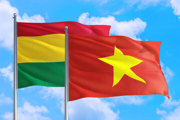 Vietnam and Bolivia national flag waving in the windy deep blue sky. Diplomacy and international relations concept.