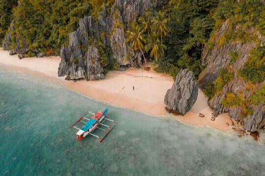 Aerial view of outrigger fishing boat on sandy beach, El Nido, the Philippines.