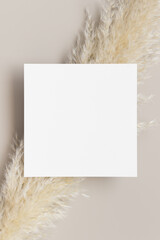 Square invitation card mockup with a pampas grass decoration.