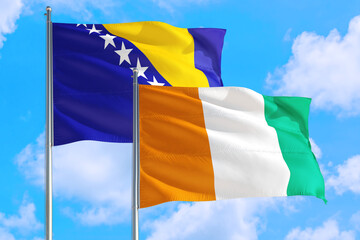Cote D'Ivoire and Bosnia Herzegovina national flag waving in the windy deep blue sky. Diplomacy and international relations concept.