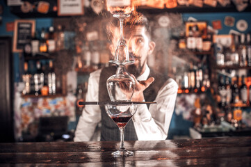Expert bartending mixes a cocktail while standing near the bar counter in pub