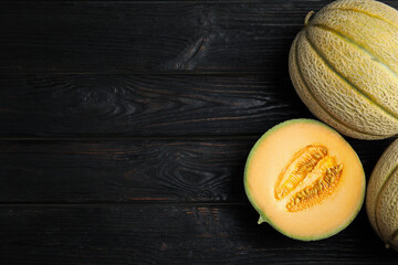 Tasty fresh melons on black wooden table, flat lay. Space for text