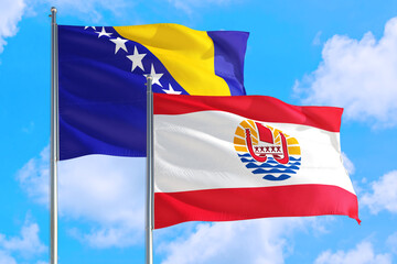 French Polynesia and Bosnia Herzegovina national flag waving in the windy deep blue sky. Diplomacy and international relations concept.