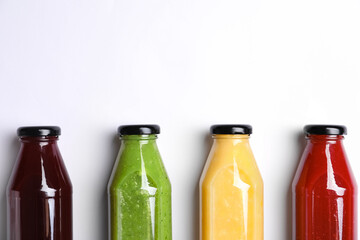 Bottles with delicious colorful juices on white background, flat lay