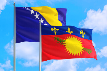 Guadeloupe and Bosnia Herzegovina national flag waving in the windy deep blue sky. Diplomacy and international relations concept.
