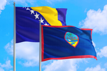 Guam and Bosnia Herzegovina national flag waving in the windy deep blue sky. Diplomacy and international relations concept.