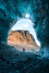 Solo female adventure traveler is discovering the ice caves in Iceland at Vatnajokull Glacier near to Jokulsarlon Glacier Lagoon. Tourism in abandoned Iceland . Outdoor living and exploring  - obrazy, fototapety, plakaty