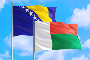 Madagascar and Bosnia Herzegovina national flag waving in the windy deep blue sky. Diplomacy and international relations concept.