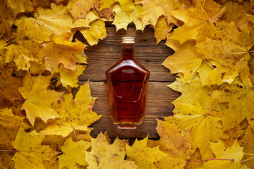 Brandy bottle on yellow maple leaves