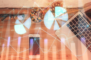 Double exposure of financial graph hologram over desktop with phone. Top view. Mobile trade platform concept.
