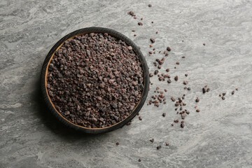 Black salt on grey table, top view. Space for text
