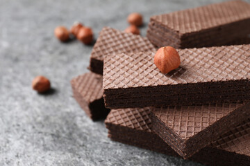 Delicious chocolate wafers and hazelnuts on grey table, closeup. Space for text