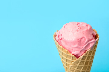 Delicious pink ice cream in waffle cone on light blue background, closeup. Space for text