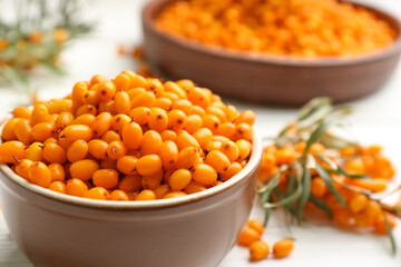 Fresh ripe sea buckthorn in bowl on white table, closeup