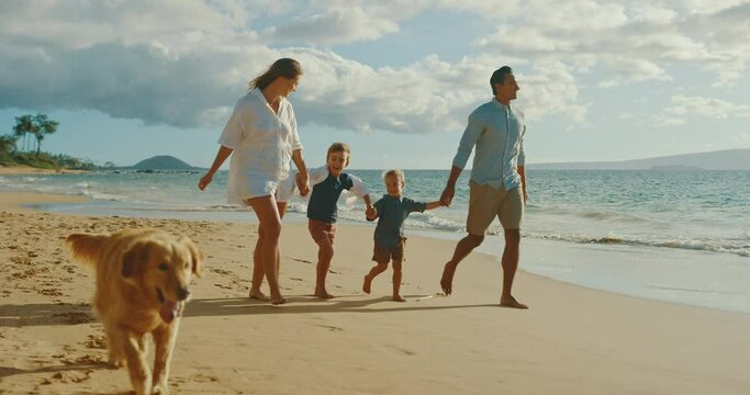 Happy young family playing with cute golden retriever dog on the beach