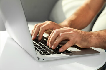Fototapeta na wymiar Man using laptop for search at white table indoors, closeup