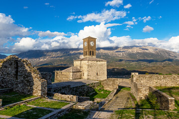 Scenic view of clock tower in castle of Gjirokastra with mountains and clouds - obrazy, fototapety, plakaty