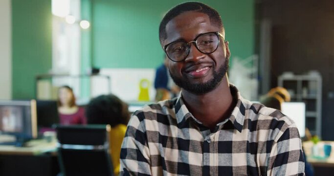 Handsome African American man in plaid shirt and glasses posing for camera. Young male office worker smiling.