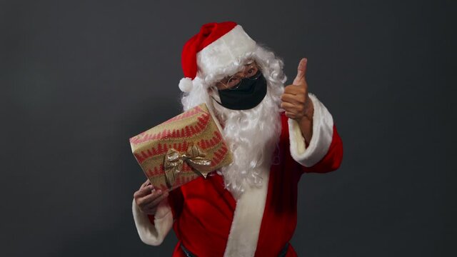 Papa noel con mascarilla pandemia dando regalo mexicano latino