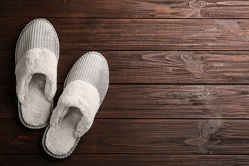 Pair of soft slippers on wooden background, flat lay. Space for text