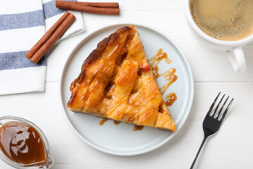 Slice of traditional apple pie served with coffee on white wooden table, flat lay