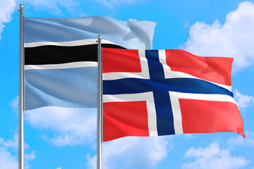 Bouvet Islands and Botswana national flag waving in the windy deep blue sky. Diplomacy and international relations concept.