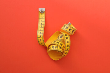 Yellow measuring tape on orange background, top view