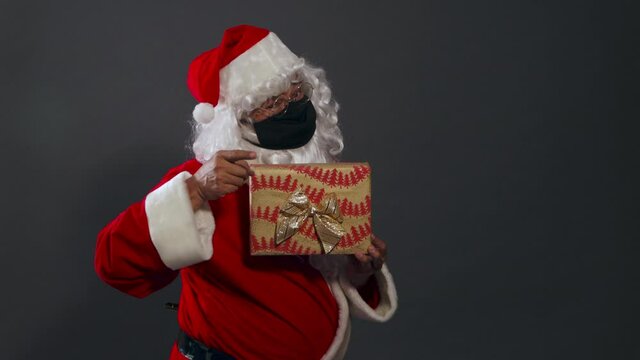 Papa noel con mascarilla pandemia dando regalo mexicano latino