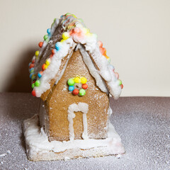 Homemade gingerbread house with icing sugar. Christmas decoration. 1x1 format. Festive food, background.