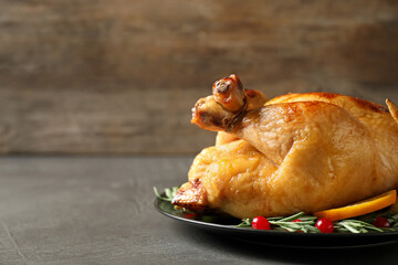 Delicious cooked turkey served with rosemary, oranges and cranberries on grey table, space for text. Thanksgiving Day celebration