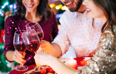 Group of happy excited beautiful friends while they are eating with glasses wine in hands at a home...